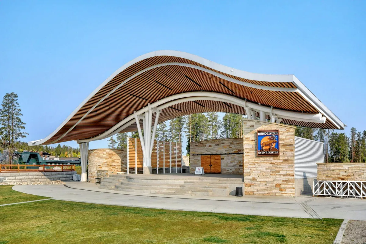 An exterior shot of a modern event center with a curved roof and stone façade, featuring prominent event signage. The setting is lively and festive, perfect for concerts, community gatherings, and seasonal festivals.